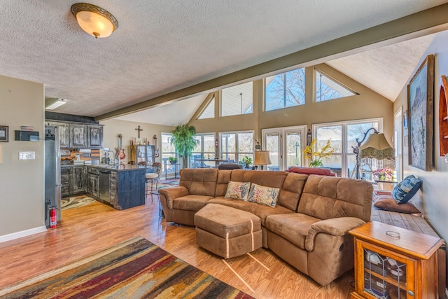 living room with vaulted ceiling with beams, light wood-type flooring, and a textured ceiling