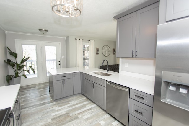 kitchen with sink, stainless steel appliances, kitchen peninsula, a chandelier, and gray cabinets