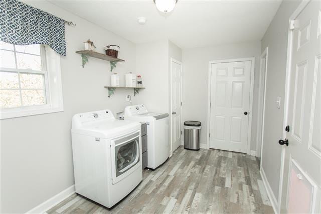 laundry room with independent washer and dryer and light hardwood / wood-style flooring