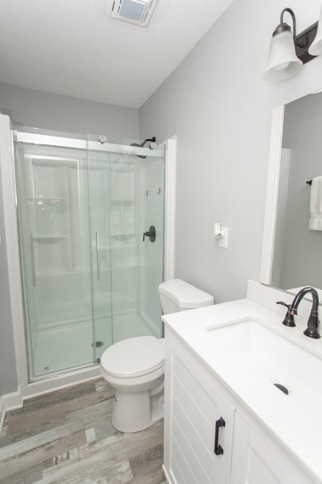 bathroom with vanity, toilet, wood-type flooring, and walk in shower