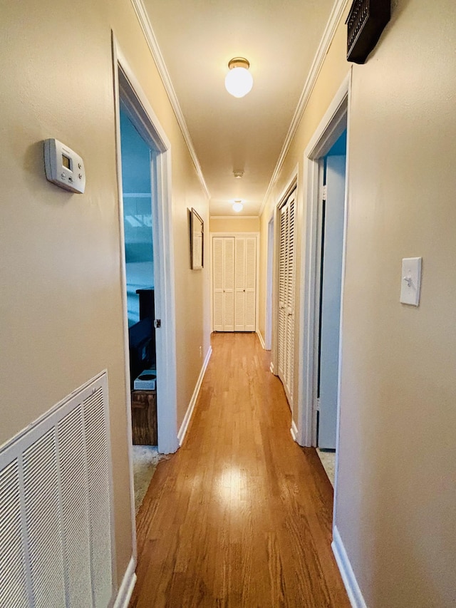 hall featuring crown molding and light hardwood / wood-style floors