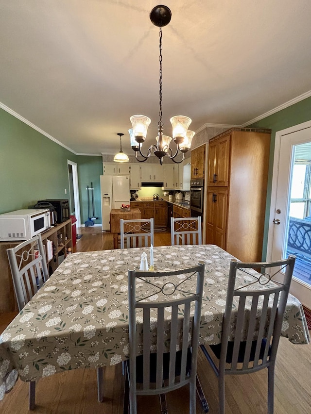 dining space featuring ornamental molding, wood-type flooring, and a notable chandelier