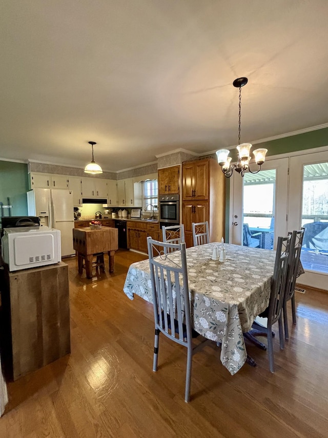 dining area featuring hardwood / wood-style flooring, ornamental molding, sink, and a notable chandelier