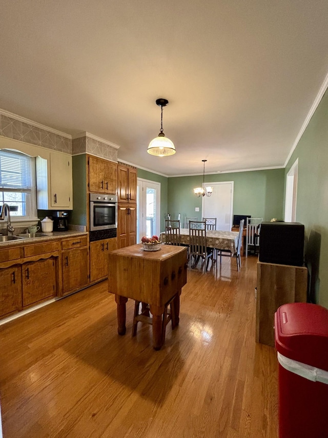 rec room featuring crown molding, sink, a chandelier, and light hardwood / wood-style flooring