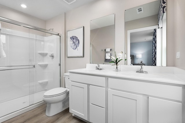 bathroom with toilet, vanity, an enclosed shower, and hardwood / wood-style flooring