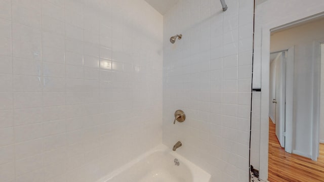 bathroom featuring wood-type flooring and tiled shower / bath