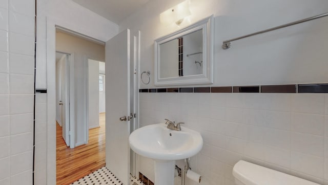 bathroom featuring sink, toilet, and tile walls