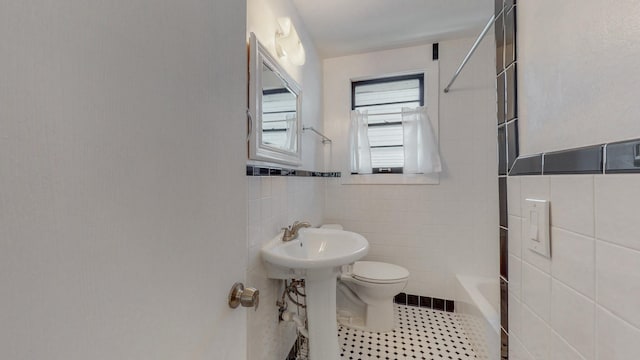 bathroom with tile patterned flooring, shower / bath combination, tile walls, and toilet