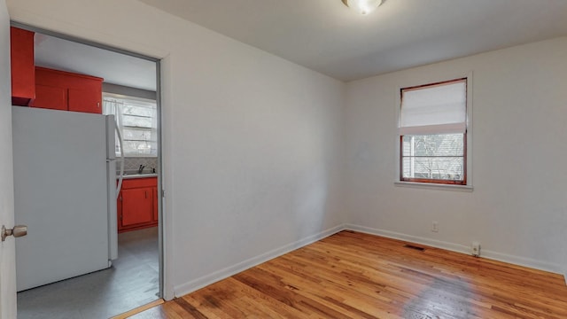 unfurnished room featuring a wealth of natural light, sink, and light wood-type flooring