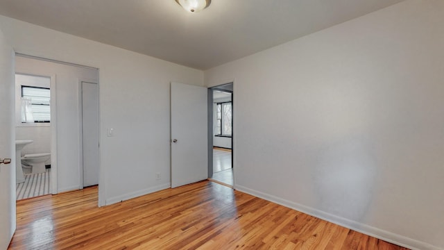 unfurnished bedroom featuring light wood-type flooring and ensuite bathroom