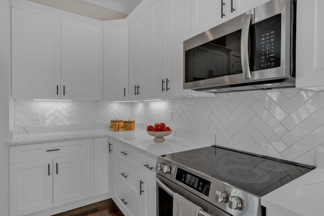 kitchen featuring appliances with stainless steel finishes, light stone counters, and white cabinetry