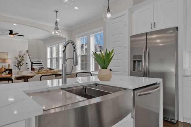 kitchen with ceiling fan, appliances with stainless steel finishes, decorative light fixtures, light stone countertops, and white cabinets