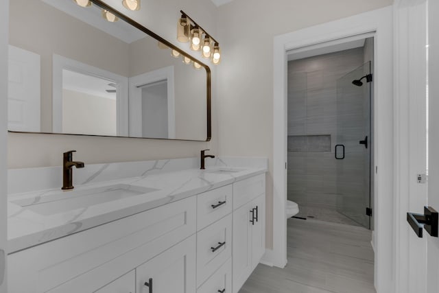 bathroom with toilet, an enclosed shower, and vanity