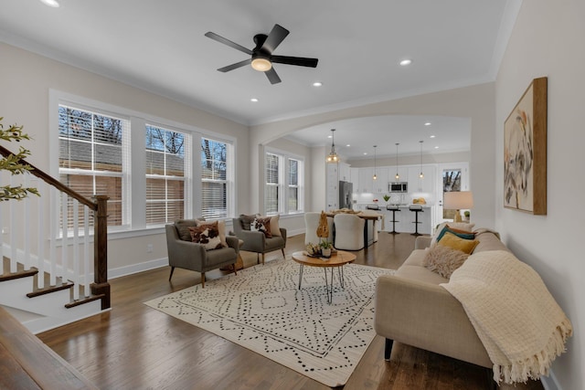 living room with dark hardwood / wood-style flooring, ceiling fan with notable chandelier, and ornamental molding