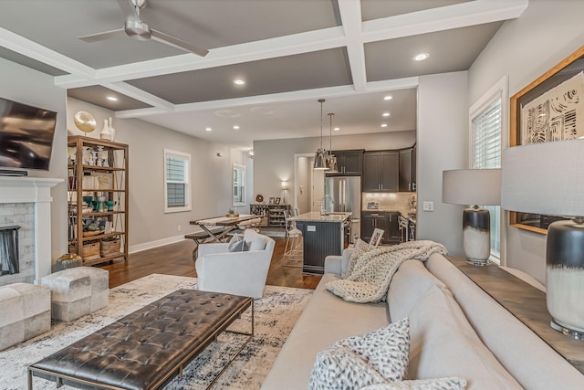 living room featuring coffered ceiling, a brick fireplace, ceiling fan, beamed ceiling, and dark hardwood / wood-style flooring