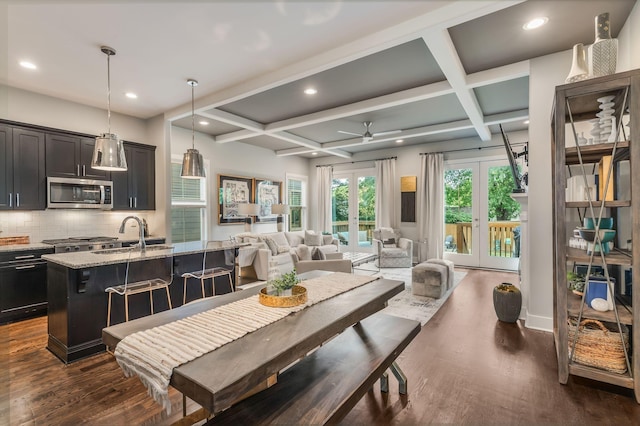 dining space with beam ceiling, french doors, sink, dark wood-type flooring, and coffered ceiling