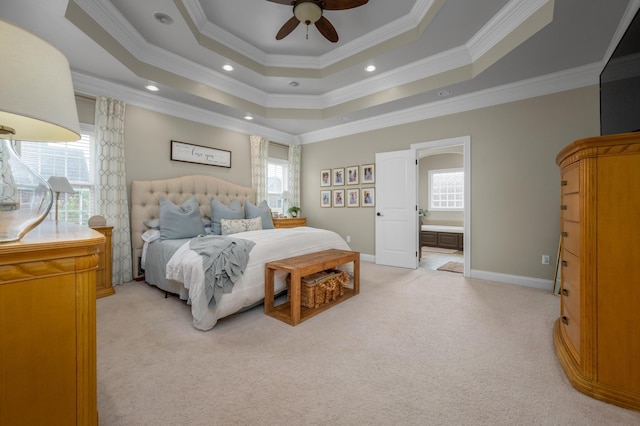 bedroom featuring ceiling fan, ensuite bath, light carpet, and a tray ceiling