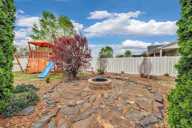 view of patio with a playground and an outdoor fire pit