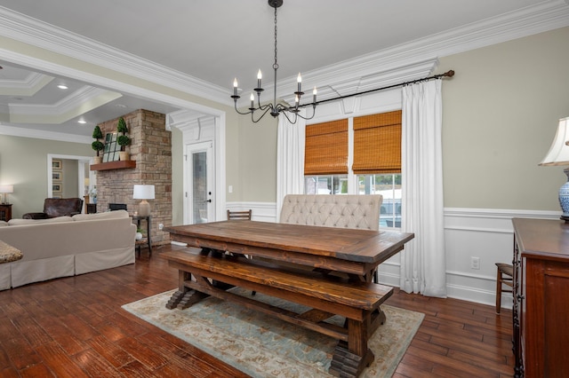 dining room featuring crown molding, a fireplace, dark hardwood / wood-style floors, and an inviting chandelier