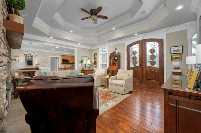 living room with french doors, hardwood / wood-style flooring, a raised ceiling, and ornamental molding