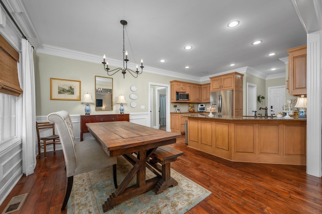 dining space with sink, dark wood-type flooring, crown molding, and a notable chandelier