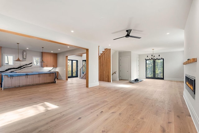 living room featuring ceiling fan with notable chandelier and light wood-type flooring