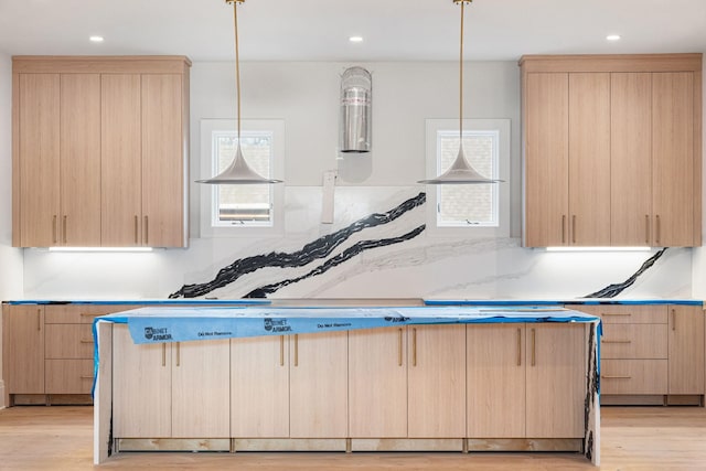 kitchen with light brown cabinets, light hardwood / wood-style floors, hanging light fixtures, and radiator