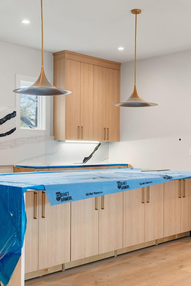 kitchen featuring light brown cabinets, light hardwood / wood-style floors, and hanging light fixtures