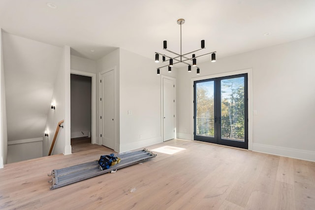 unfurnished room with hardwood / wood-style flooring, a chandelier, and french doors