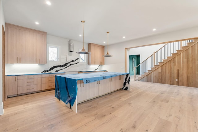 kitchen with a kitchen breakfast bar, a spacious island, light hardwood / wood-style floors, decorative light fixtures, and light brown cabinetry