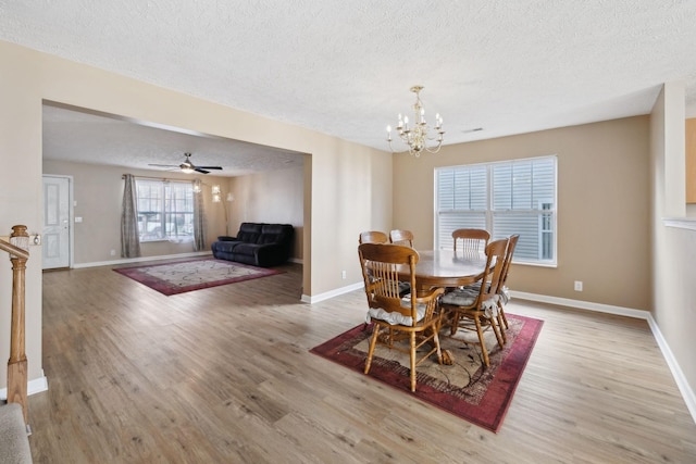 dining room featuring a textured ceiling, a notable chandelier, and light wood-type flooring