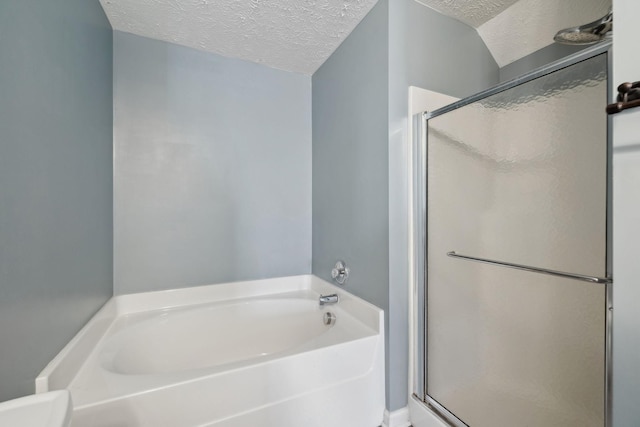 bathroom with a textured ceiling and separate shower and tub