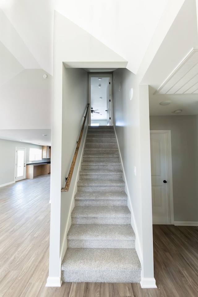 stairway with hardwood / wood-style flooring and lofted ceiling