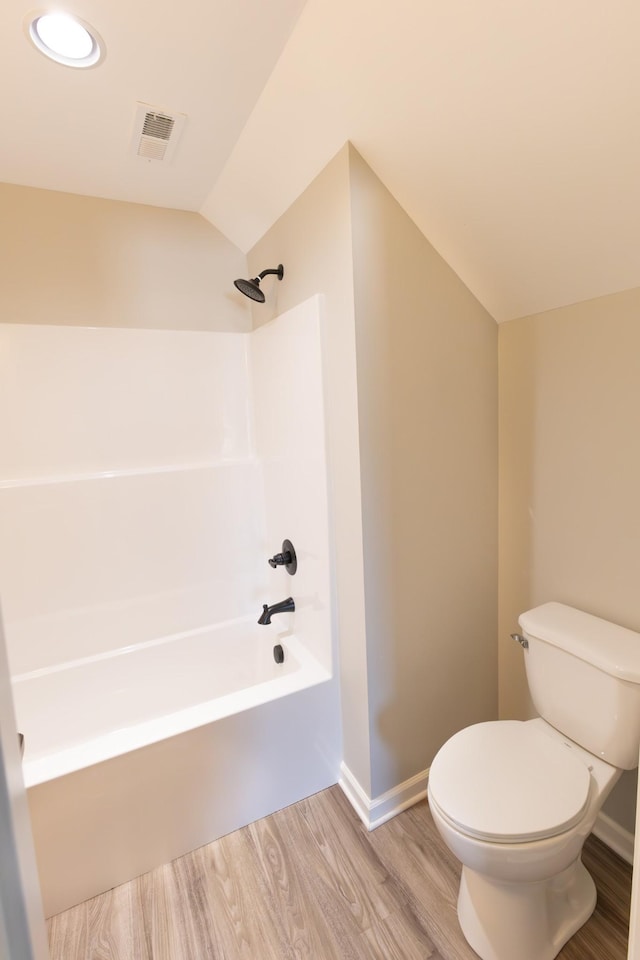 bathroom featuring shower / tub combination, toilet, wood-type flooring, and vaulted ceiling