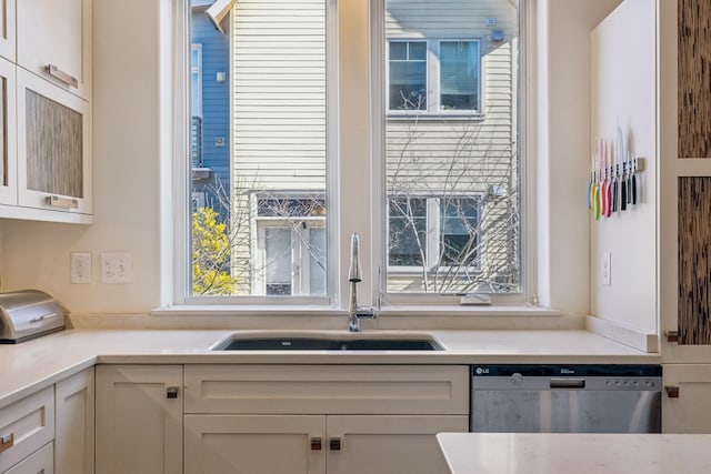 kitchen with dishwasher, white cabinets, and sink