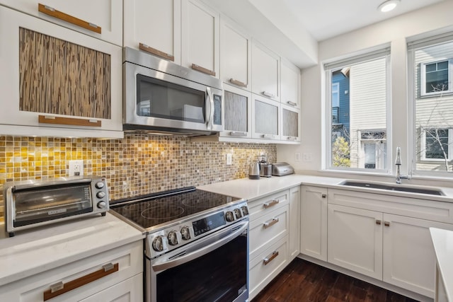 kitchen with sink, dark wood-type flooring, stainless steel appliances, tasteful backsplash, and white cabinets