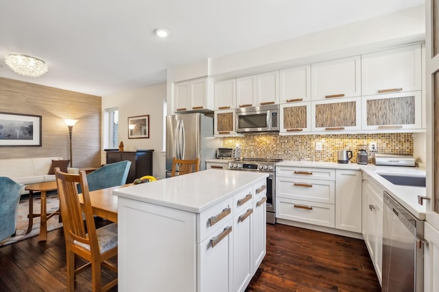 kitchen with tasteful backsplash, white cabinets, dark wood-type flooring, and appliances with stainless steel finishes