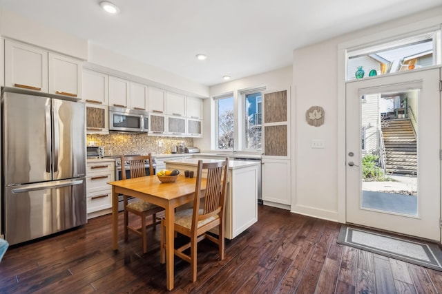 kitchen featuring dark hardwood / wood-style floors, white cabinetry, stainless steel appliances, and tasteful backsplash