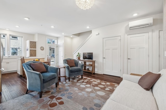 living room featuring dark hardwood / wood-style floors, an inviting chandelier, and a wall mounted AC