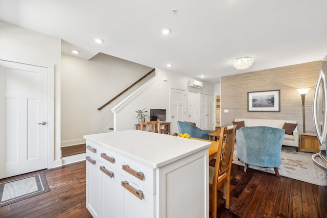 kitchen with white cabinets, dark hardwood / wood-style flooring, a kitchen island, and a wall unit AC