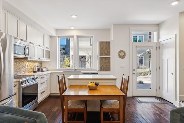 kitchen with appliances with stainless steel finishes, tasteful backsplash, dark wood-type flooring, sink, and white cabinetry