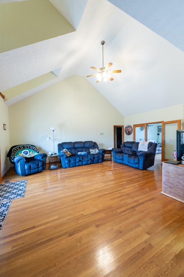 living room featuring ceiling fan, vaulted ceiling, and light wood-type flooring