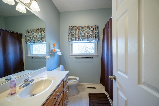 bathroom featuring plenty of natural light, tile patterned floors, toilet, and vanity