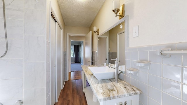 bathroom with hardwood / wood-style floors, a textured ceiling, vanity, and tile walls