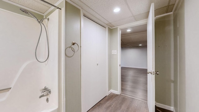 bathroom featuring washtub / shower combination, wood-type flooring, and a drop ceiling