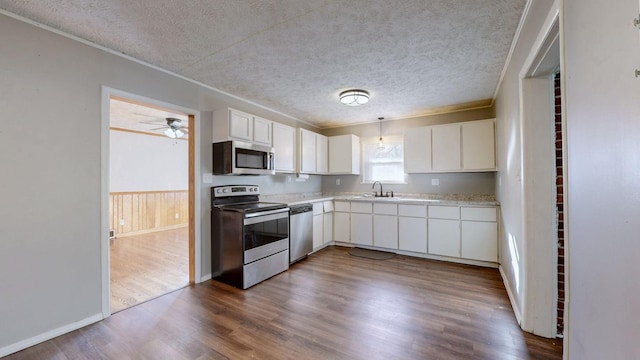 kitchen with white cabinets, stainless steel appliances, hanging light fixtures, and a textured ceiling