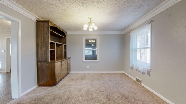 unfurnished dining area featuring ornamental molding, light colored carpet, an inviting chandelier, and a textured ceiling