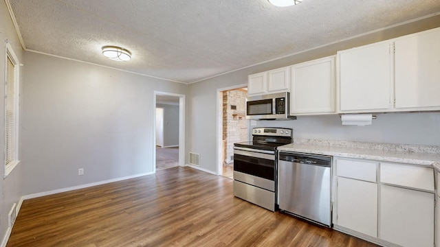 kitchen featuring light hardwood / wood-style floors, white cabinetry, appliances with stainless steel finishes, and a textured ceiling