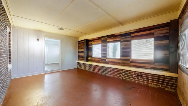 unfurnished room with concrete floors and wood walls