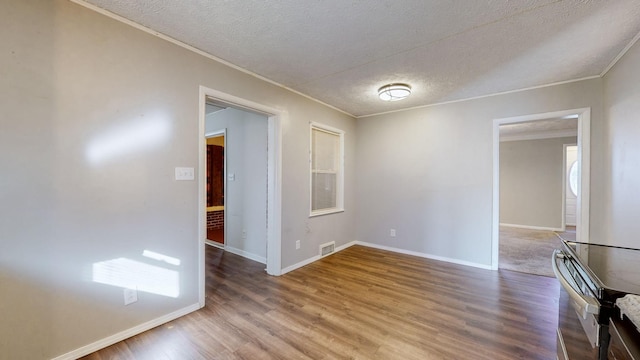 empty room featuring crown molding, hardwood / wood-style floors, and a textured ceiling